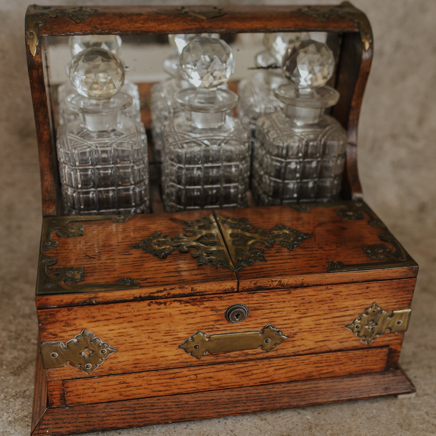 Antique Oak and Brass Inlaid Tantalus with Three Cut Crystal Decanters & Secret Game Drawer